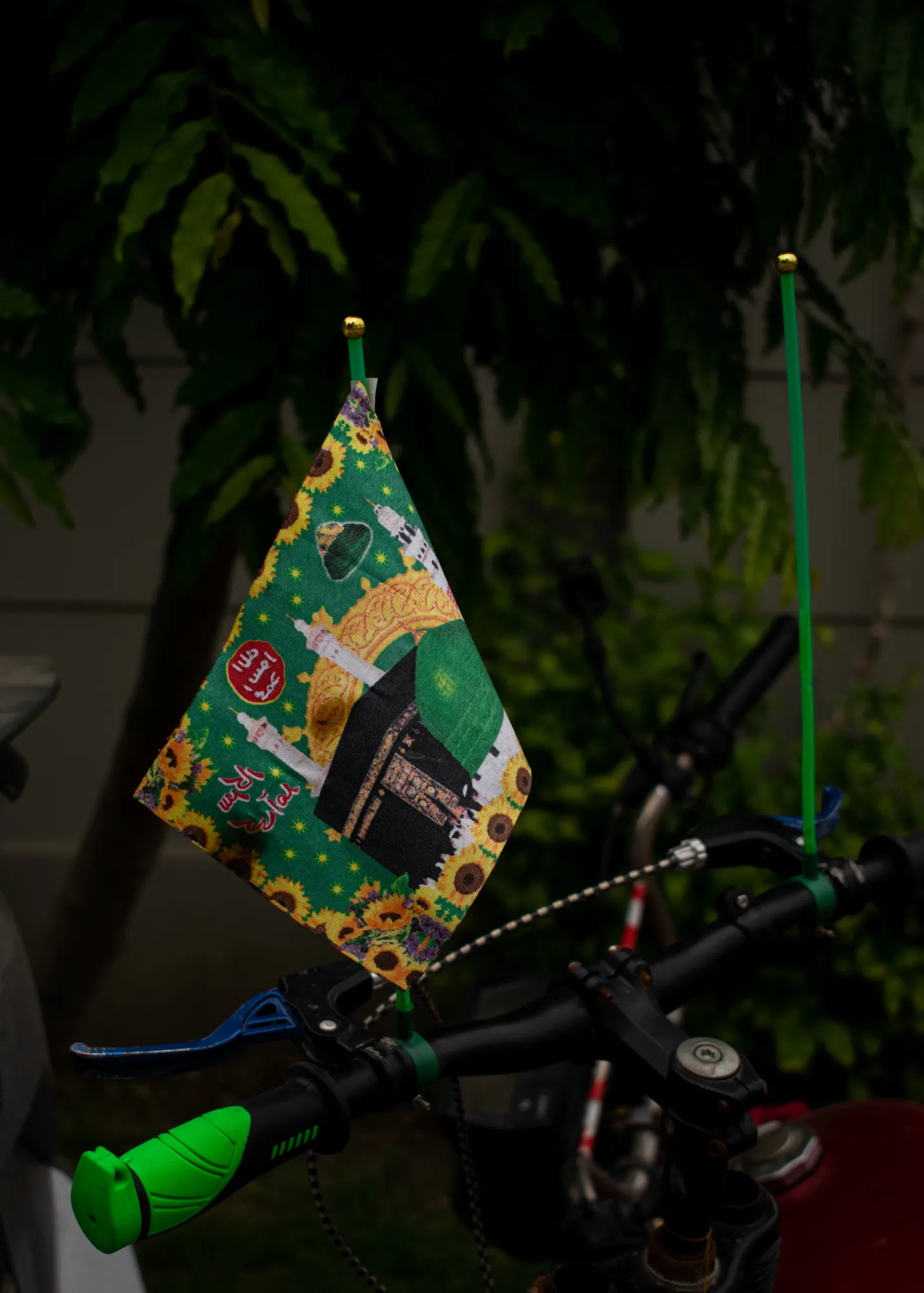 A bike adorned with flag parked outside a house serving tabarakaat