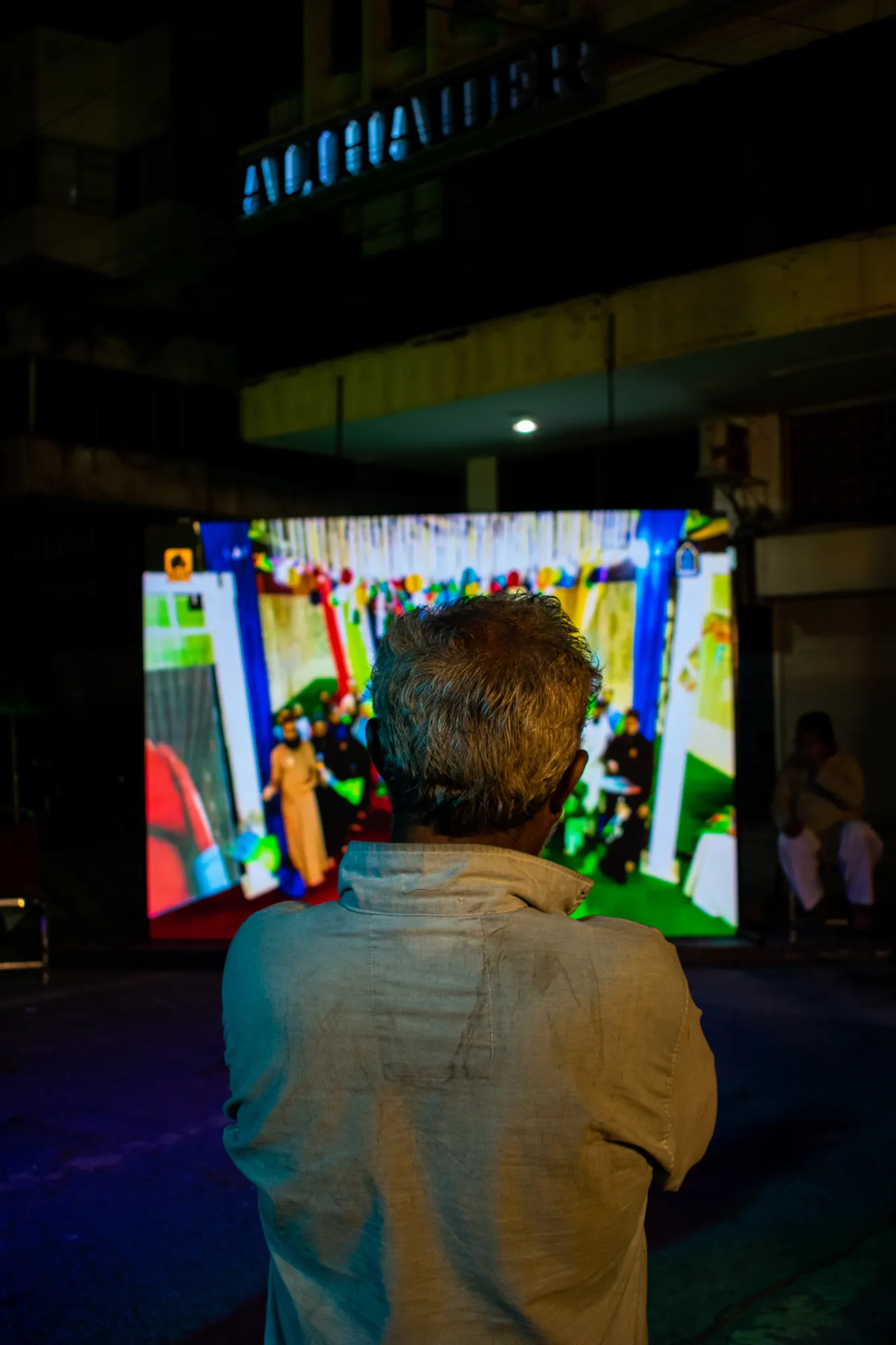 A person on the road watching a screen playing videos of naat