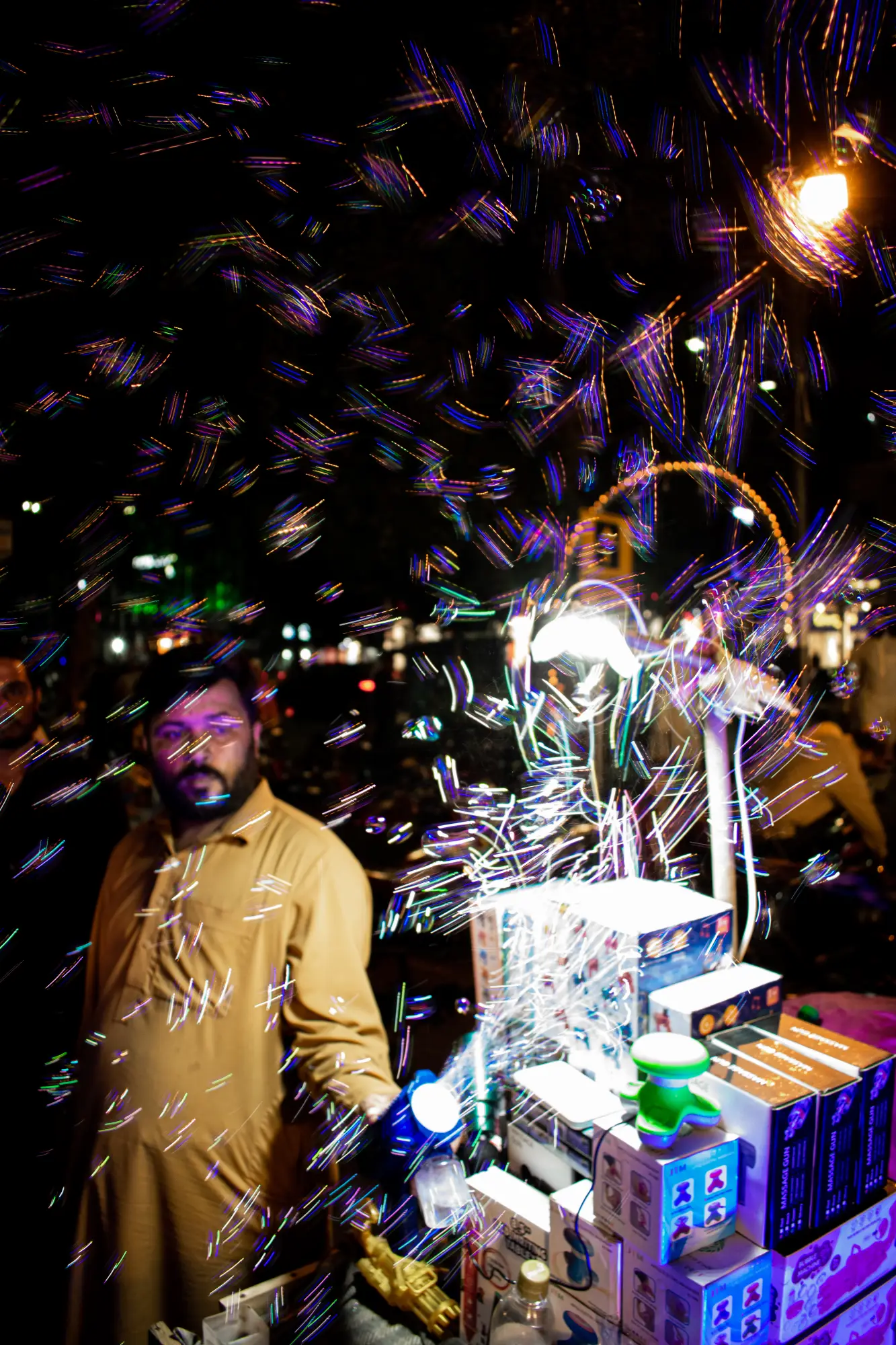 A vendor giving a demo of his bubble gun, filling the air with soap bubbles, to attract children at the celebration