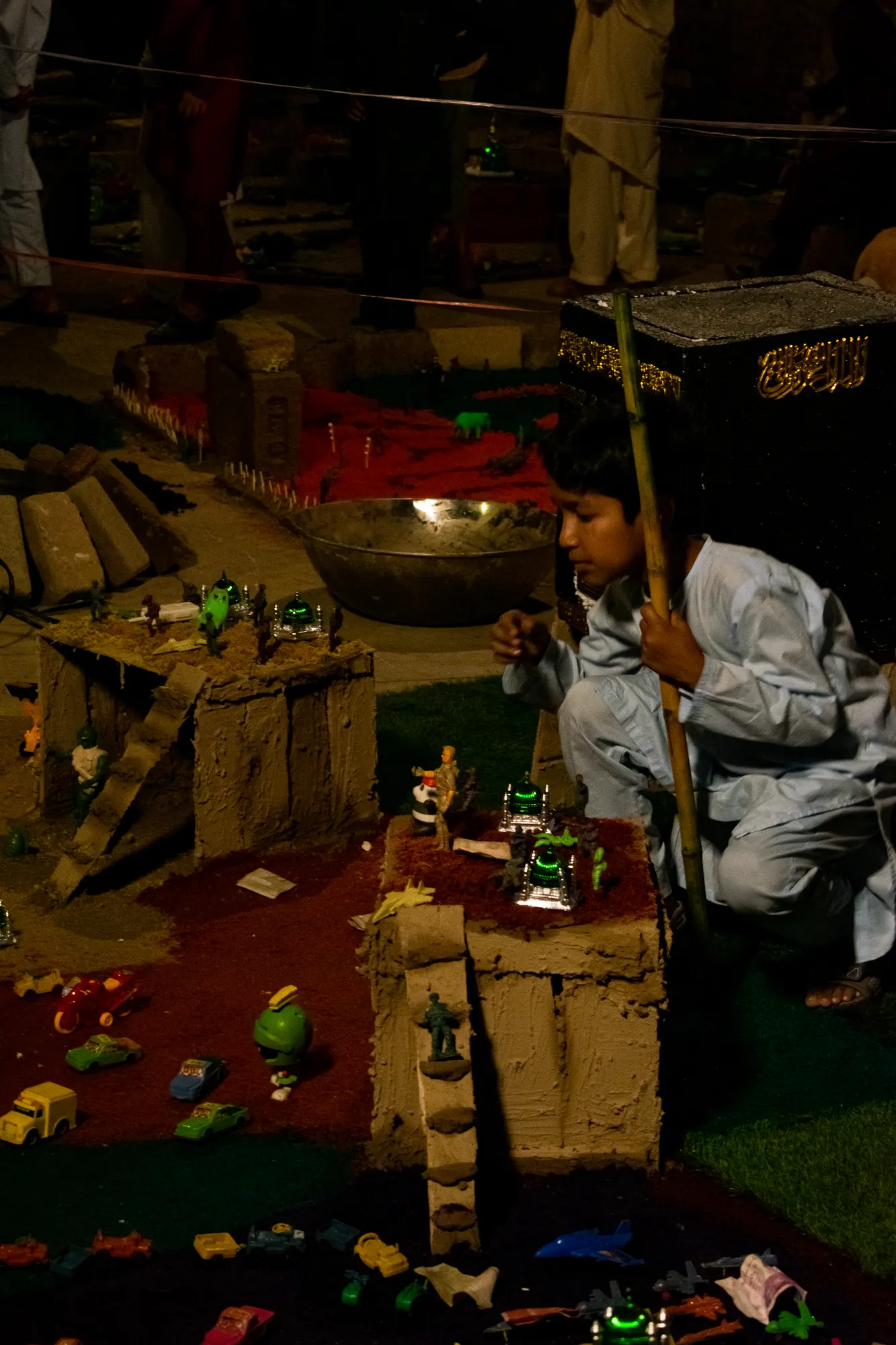 A little boy carefully inspecting his model of a small town populated by his toys