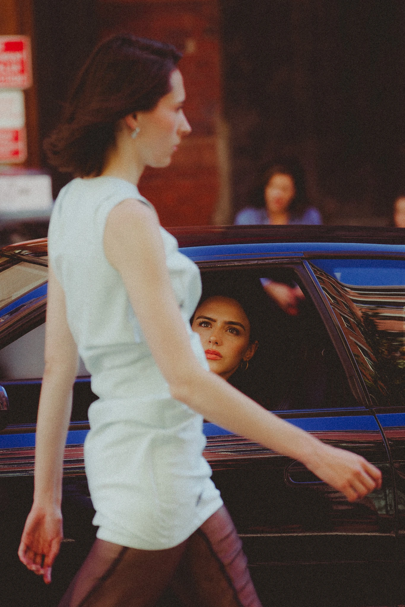 A woman in a car watching the model walk down the street